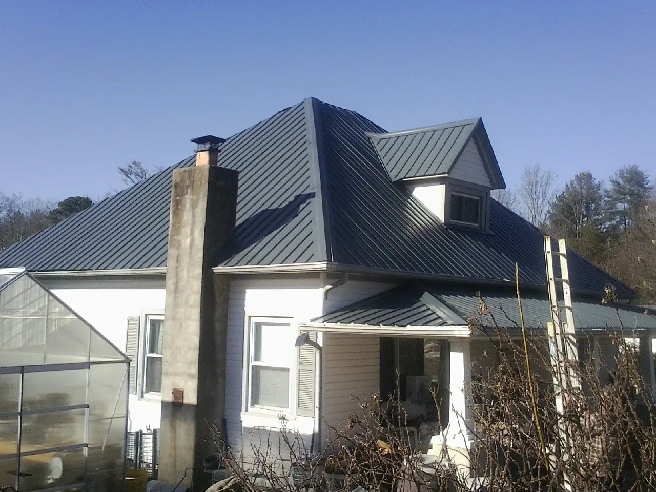 Dark blue standing seam metal roof on a white farmhouse with dormer — Slate & Tile Roof Repair by Roofing Brothers in Andalusia