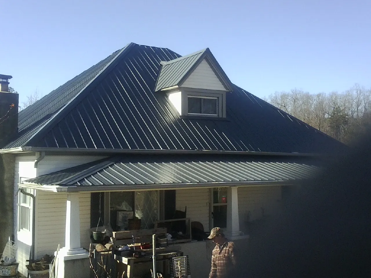 Dark blue standing seam metal roof with a dormer above a front porch in Andalusia