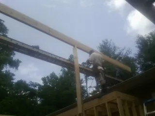 Carpenter setting a ridge beam over a new addition frame — Ice Dam Removal by Roofing Brothers in Andalusia
