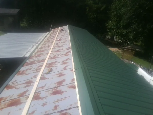 Old rusted panels beside newly installed green metal roofing — Wind Damage Roof Repair by Roofing Brothers in Andalusia