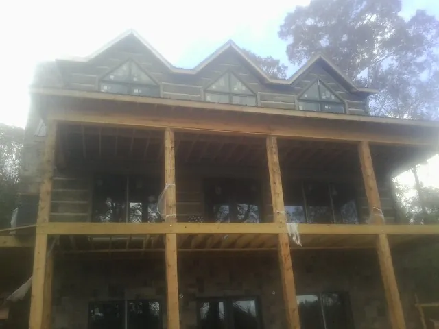 Dormers and porch framing on a large log home under construction — Roof Coating work by our crew in Andalusia
