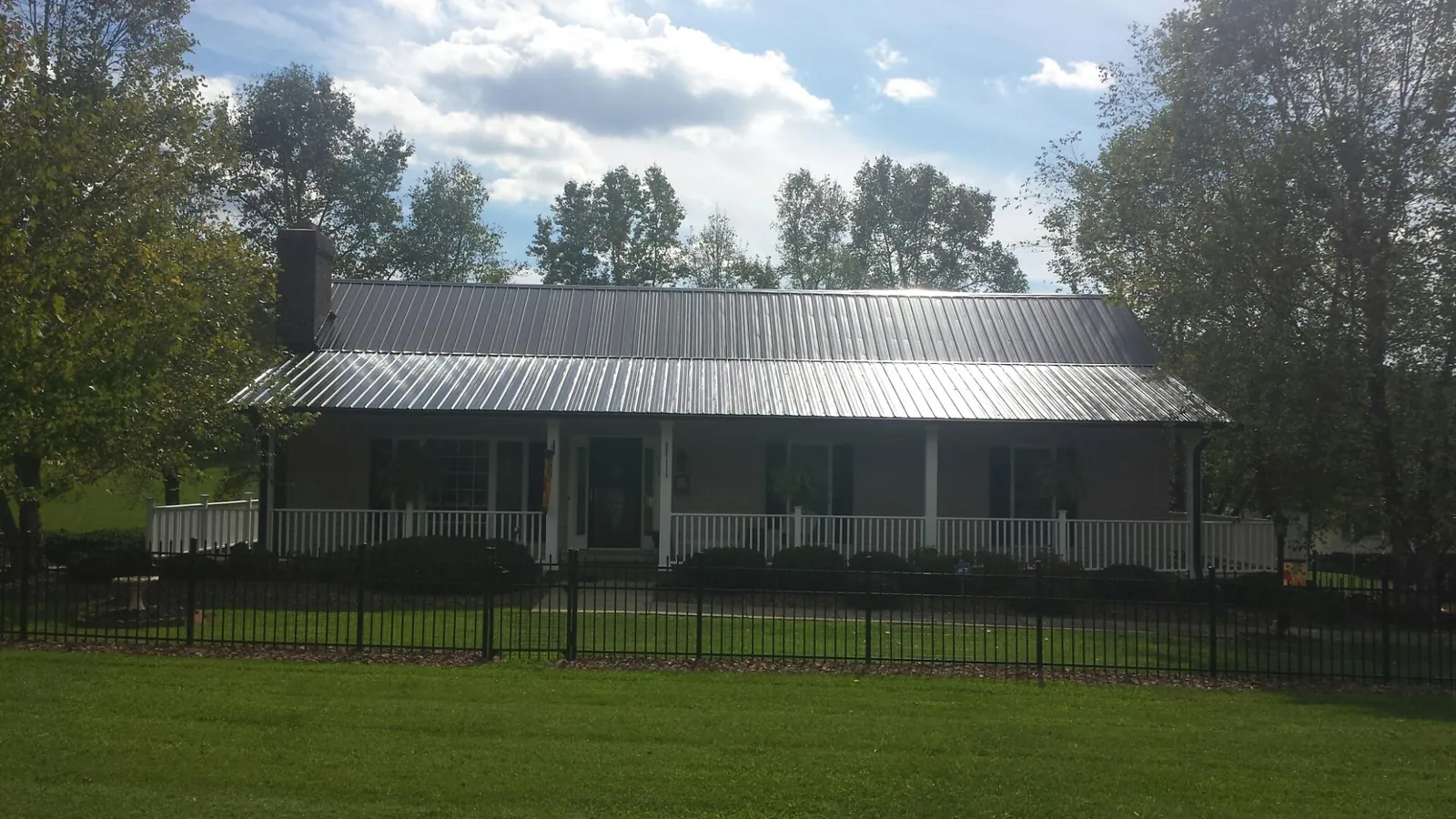 Gray metal roof on a brick ranch with a full width front porch — Gutter Guard Installation work by our crew in Andalusia