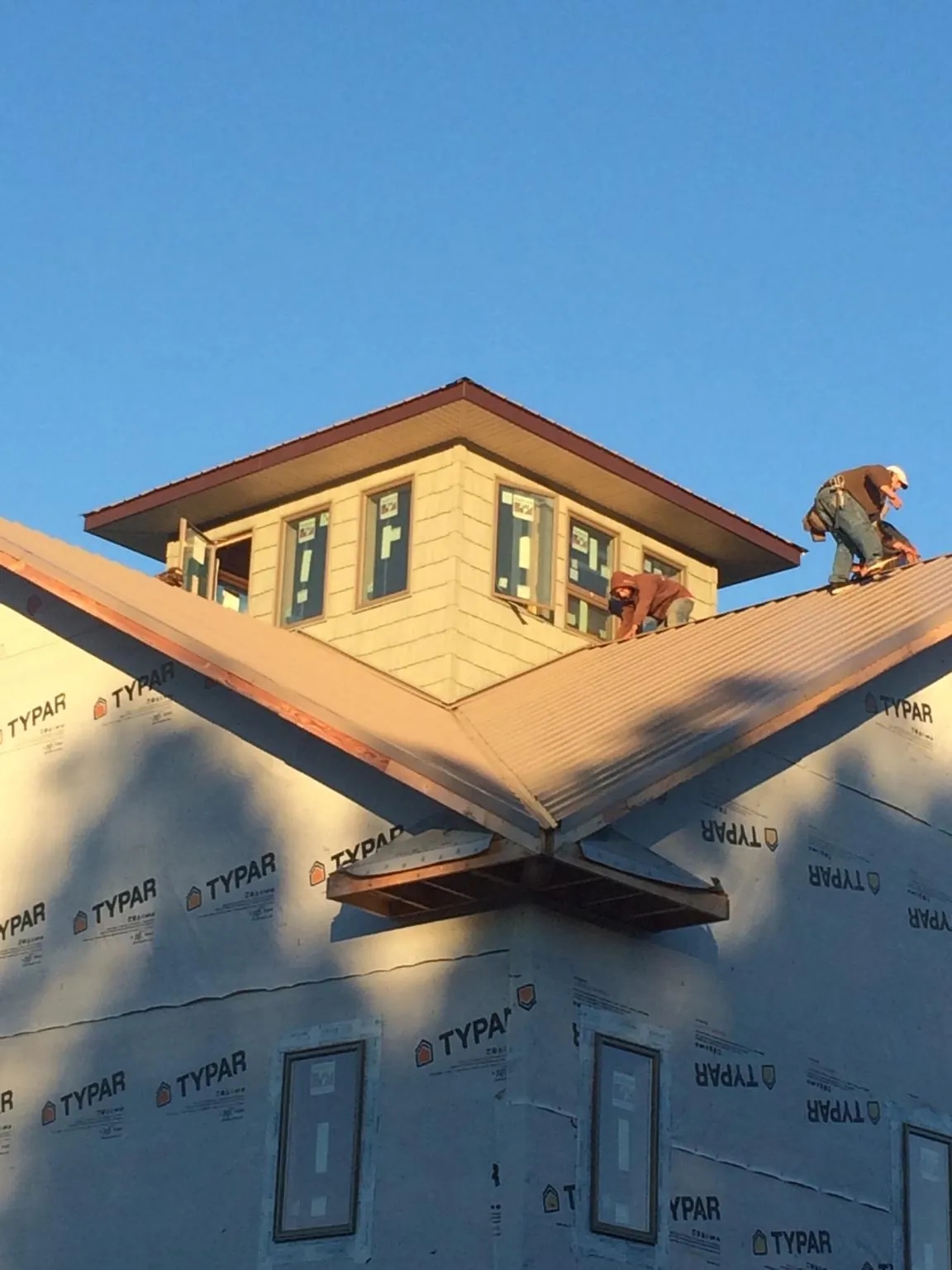Roofers working around a rooftop cupola on a new metal roof at sunset — Roof Waterproofing in Andalusia by Roofing Brothers